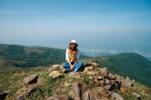woman sitting on the peak of a mountain